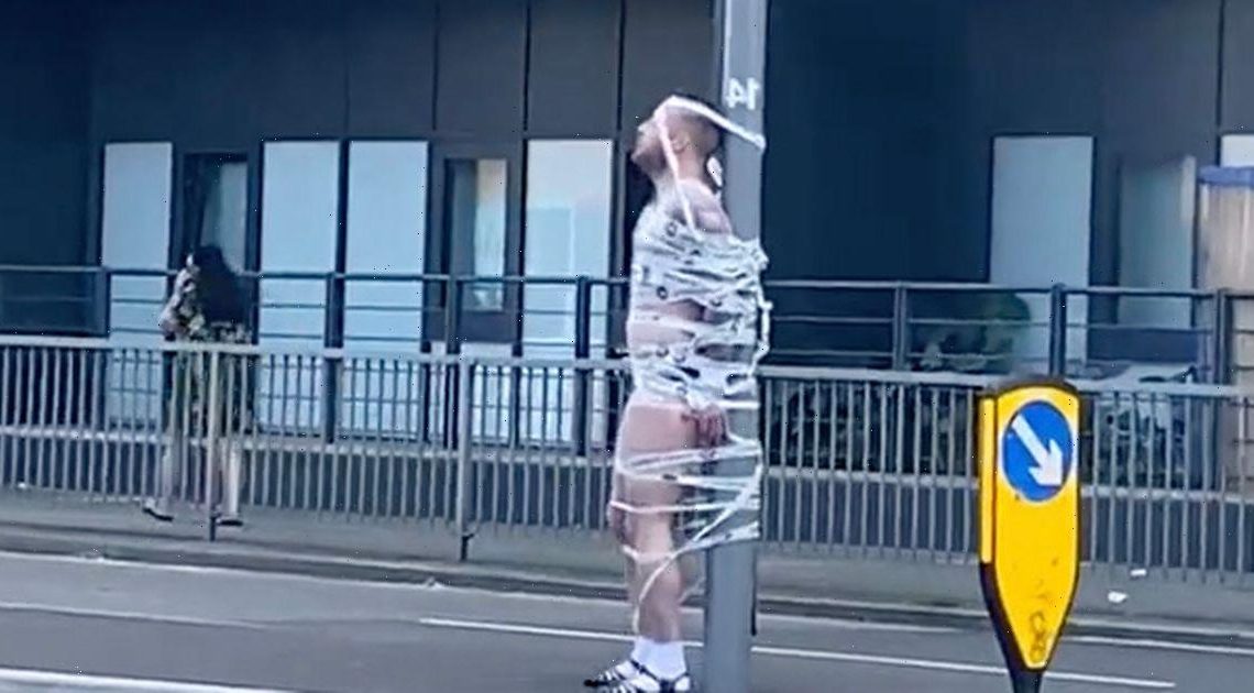 Watch moment topless groom taped to traffic lights outside pub in stag do prank